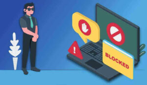عکس: مرد سر بر دست لپ‌تاپ با پیام "blocked" و نشانه‌های مسدود شدن.